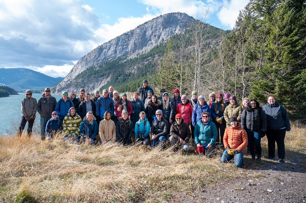 NCC staff members pose for a photo in a mountainous landscape near a lake.