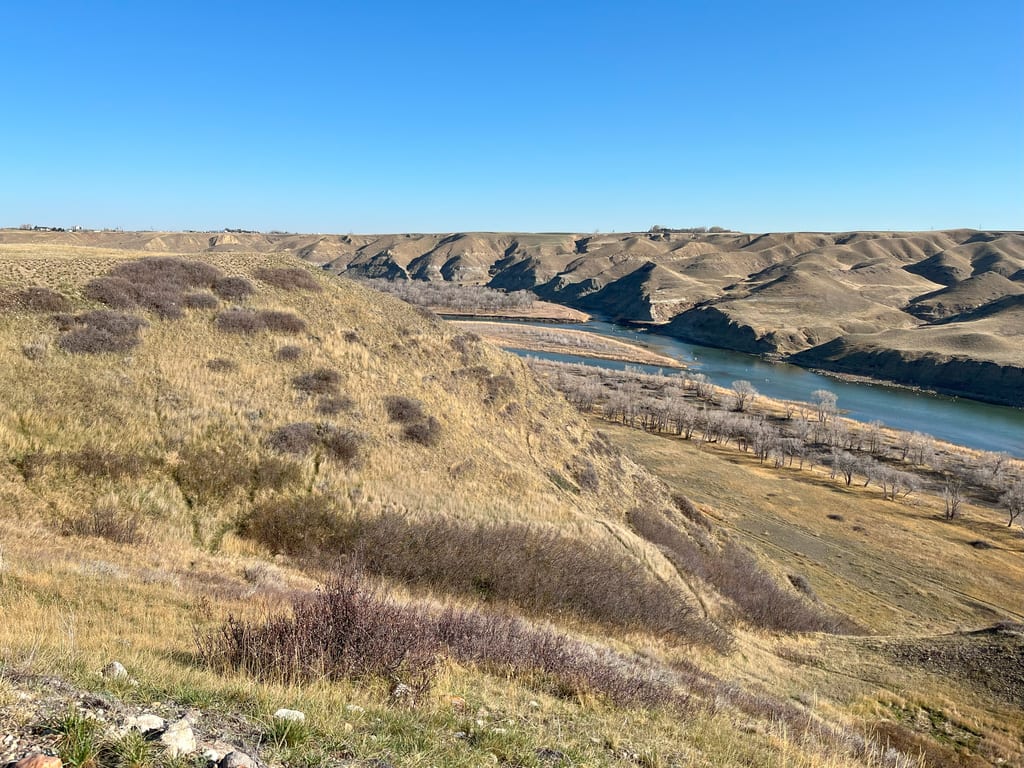 A river winds through a landscape of rolling hills and dry grasslands.