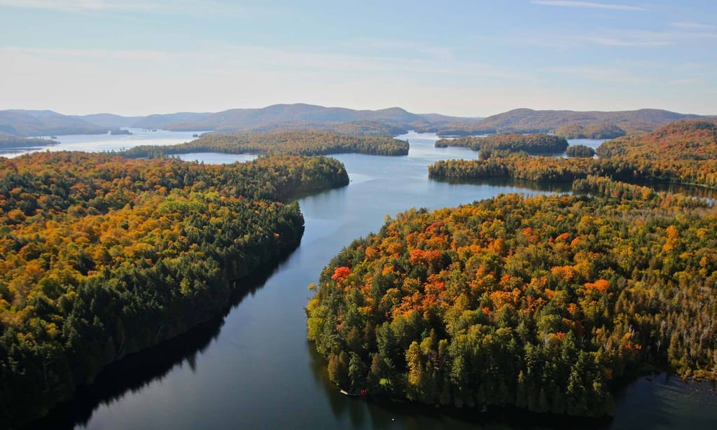 An aerial view of a river winding through forested islands with autumn foliage.