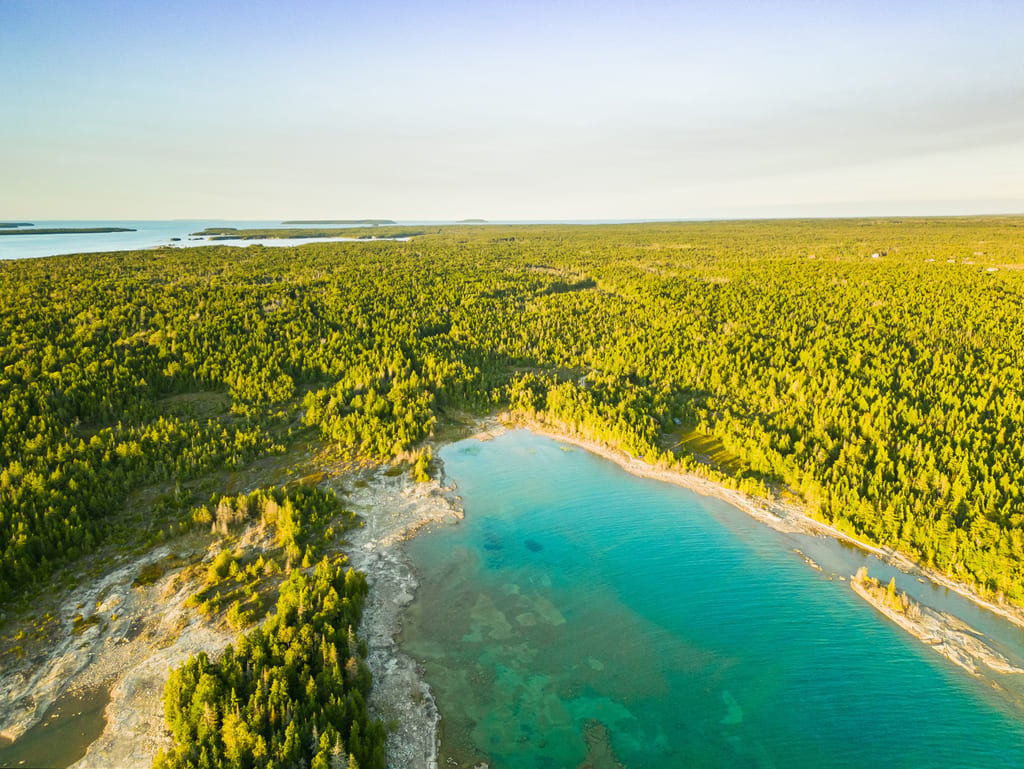 An aerial view of a turquoise lake surrounded by a dense green forest.