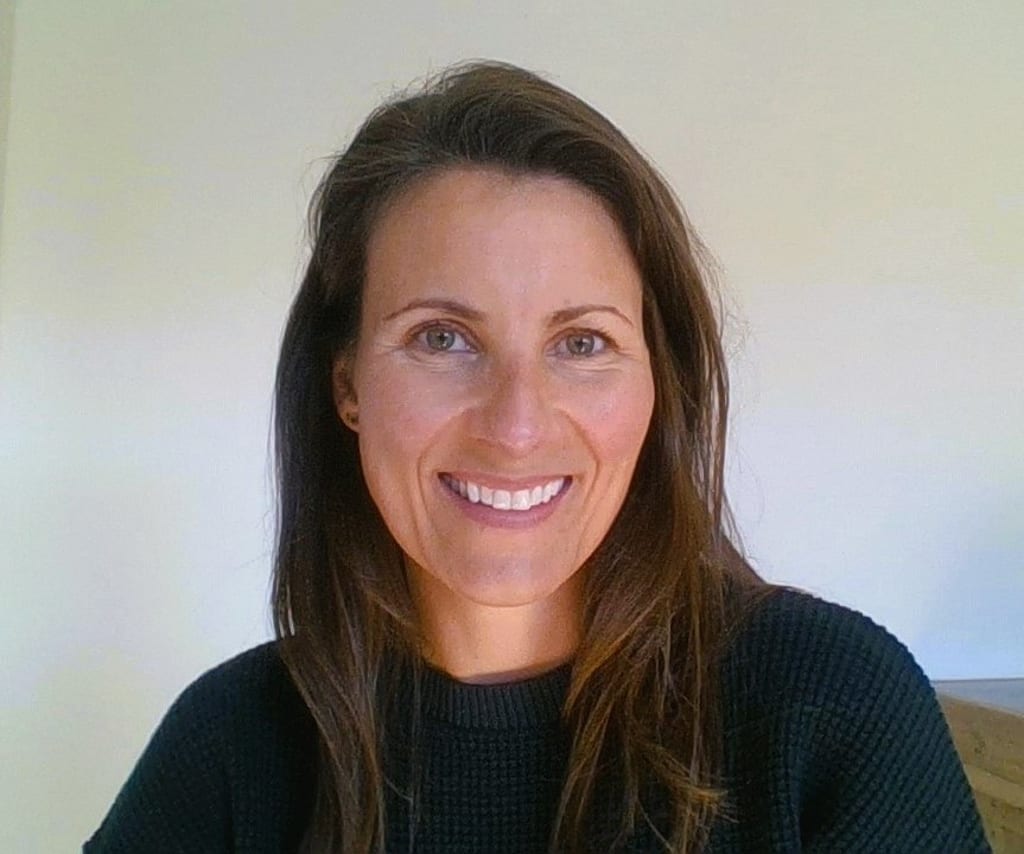 A woman with long brown hair smiles at the camera.