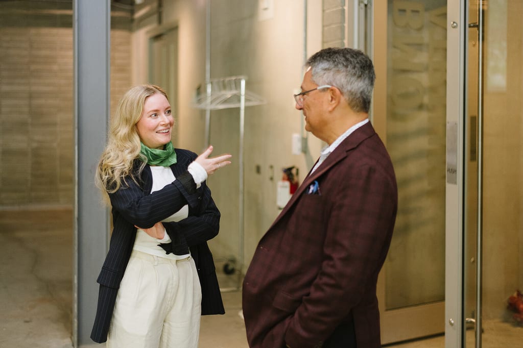 A woman gestures while talking to a man in a modern indoor setting.