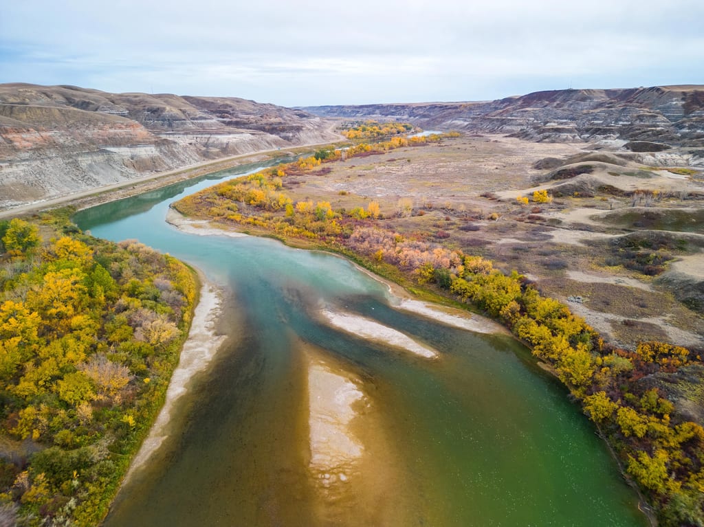 An aerial view of a winding river surrounded by autumn-colored trees and rolling hills.